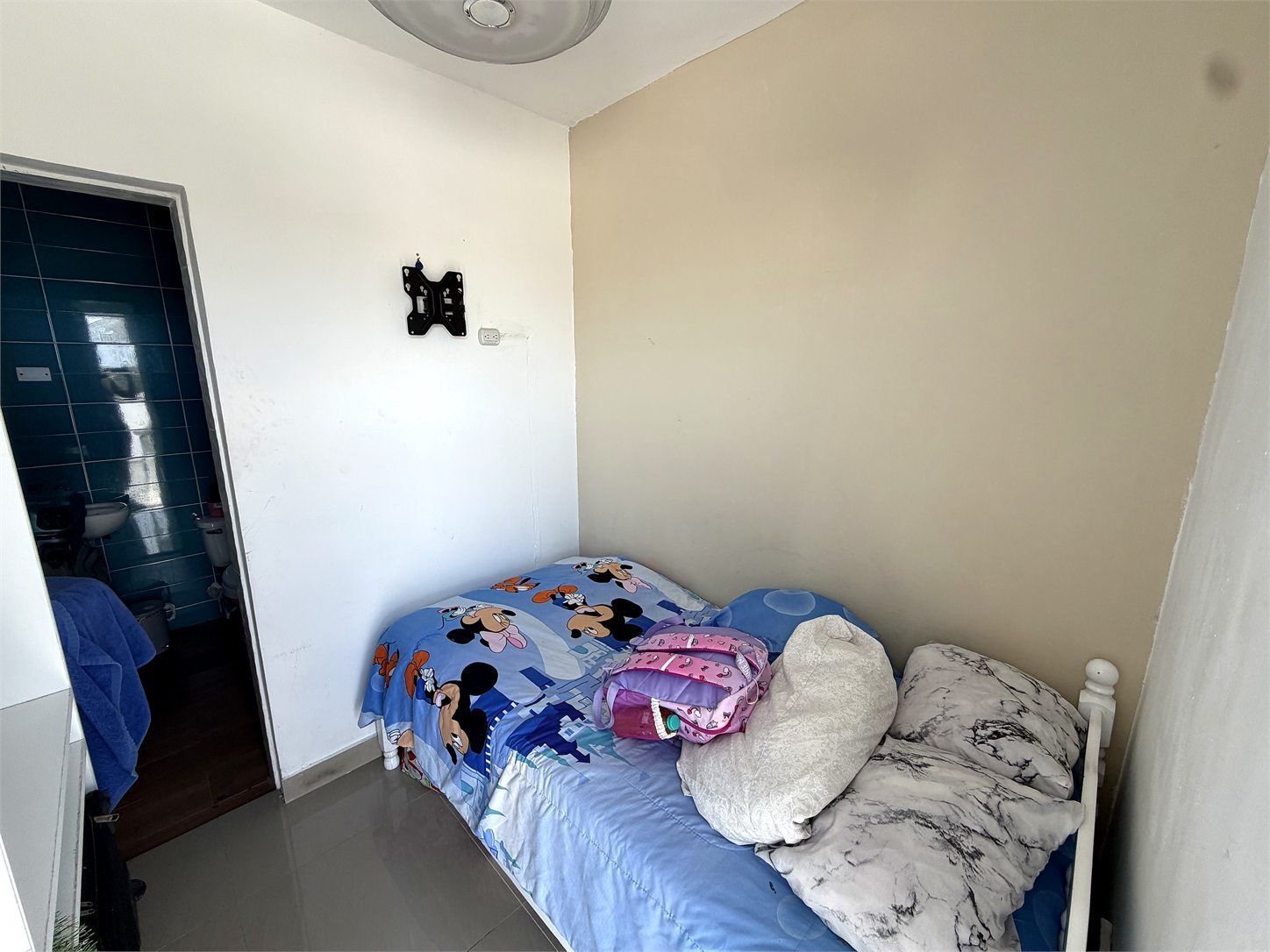 Cuarta habitación compacta con cama individual y acceso visible a un baño