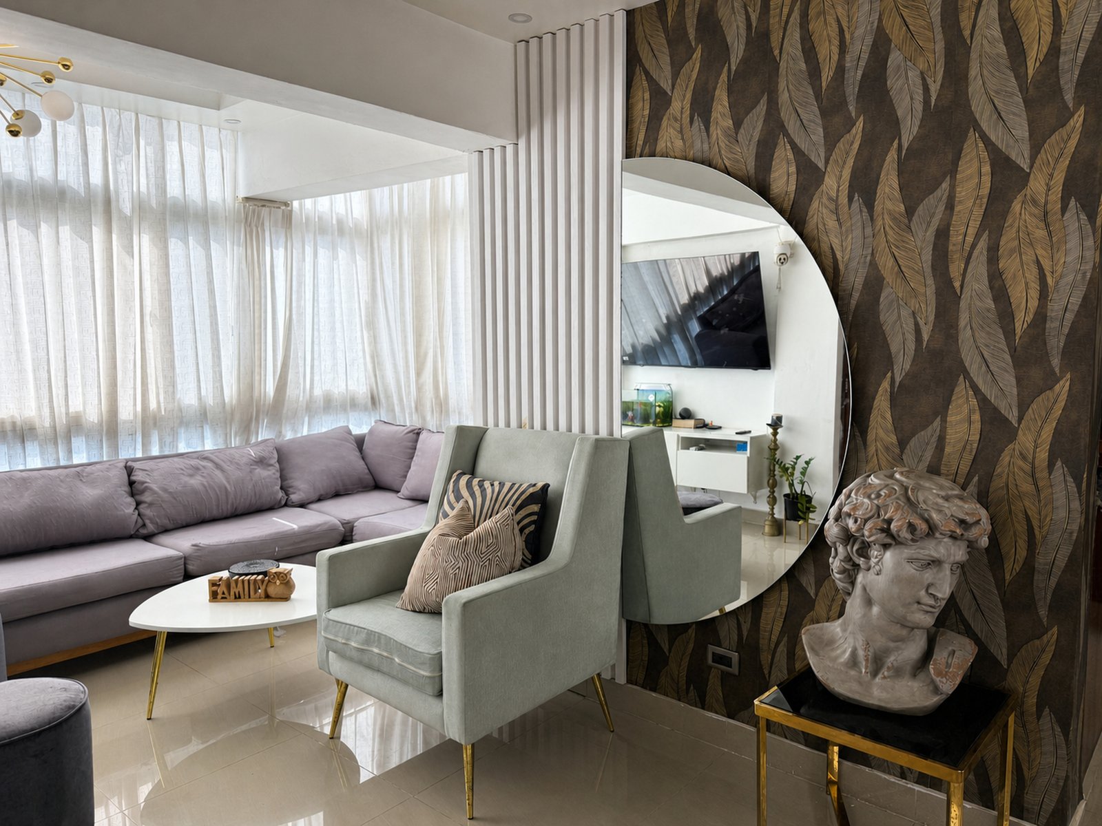 Sala principal con ventanales, sofá, butacas y pared decorativa