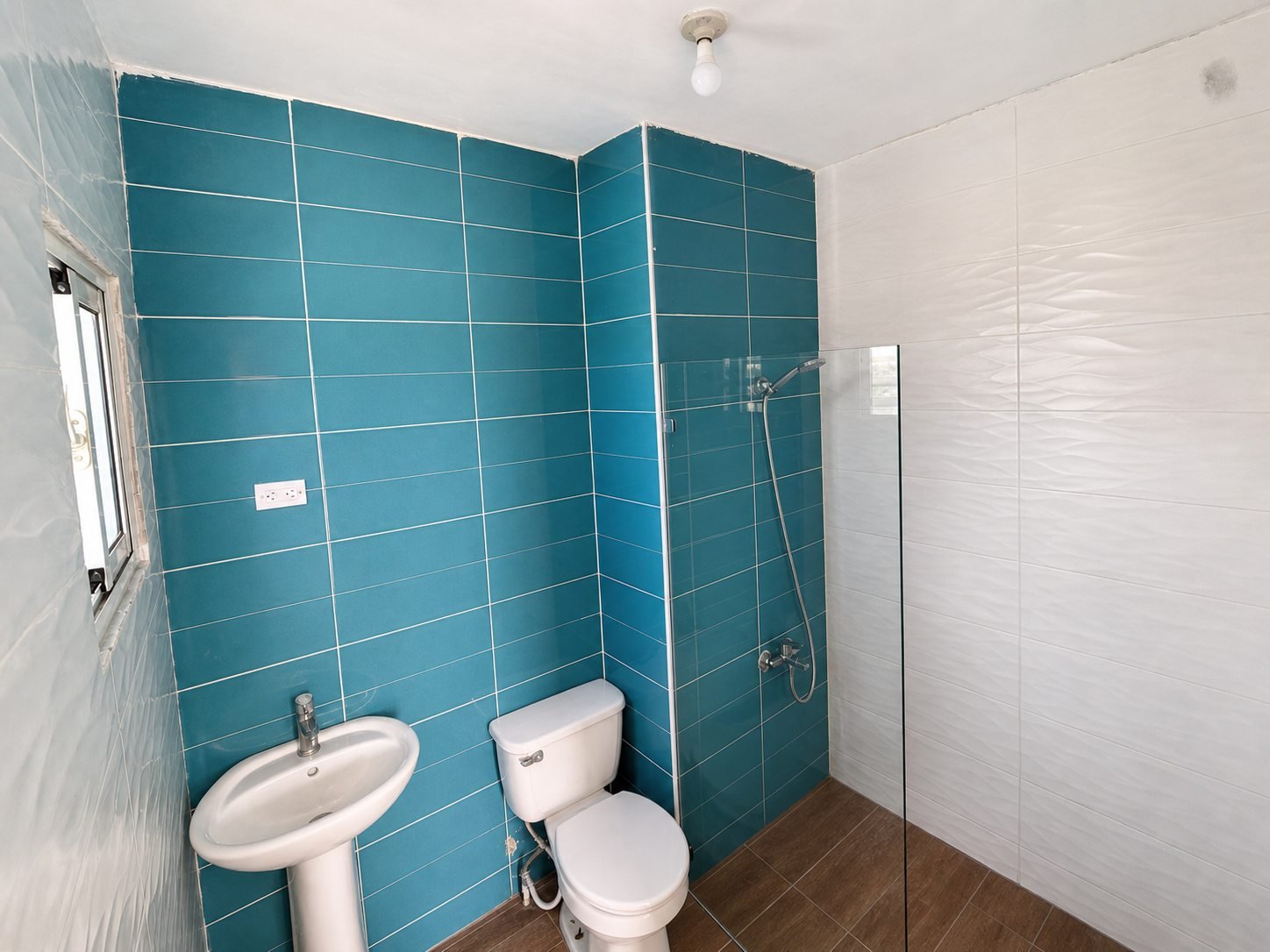 Baño secundario con revestimiento azul y área de ducha