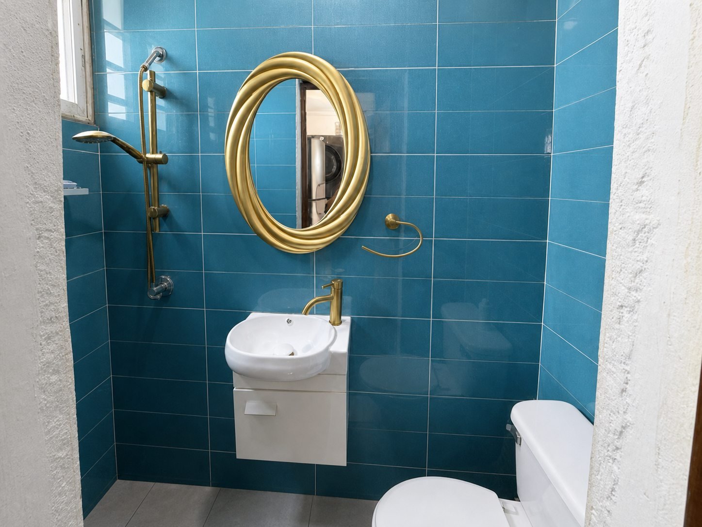 Baño secundario con revestimiento azul, espejo redondo y lavabo