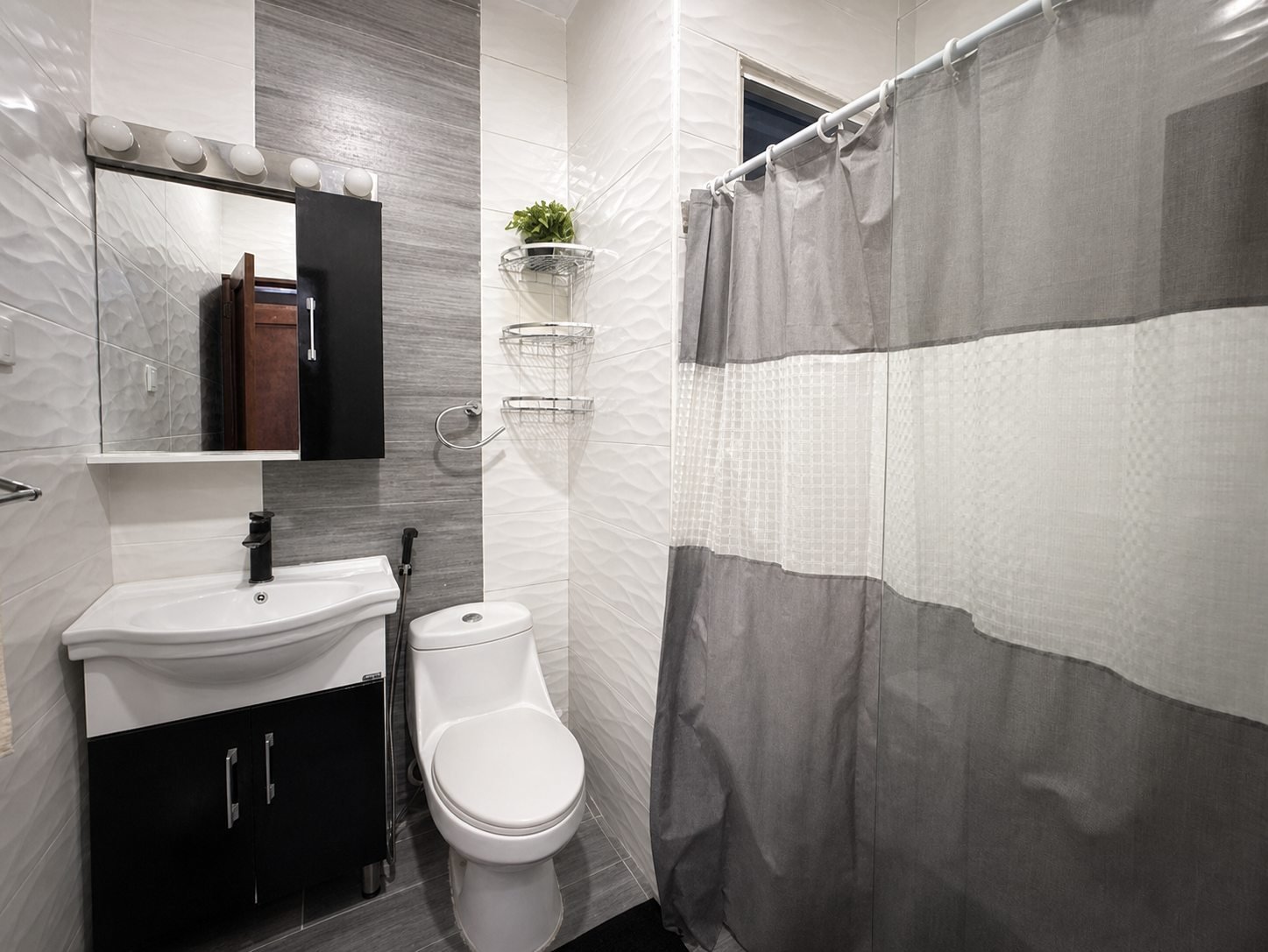 Baño secundario con revestimiento gris, lavabo y ducha