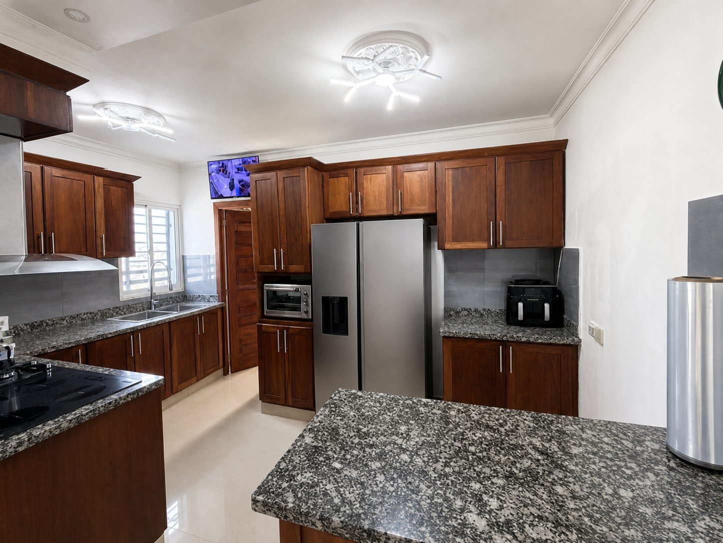 Cocina con gabinetes de madera, topes de granito y amplias superficies de trabajo